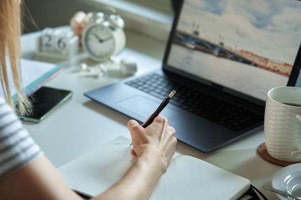 istock Woman sitting at table by the window and using laptop 1443206376