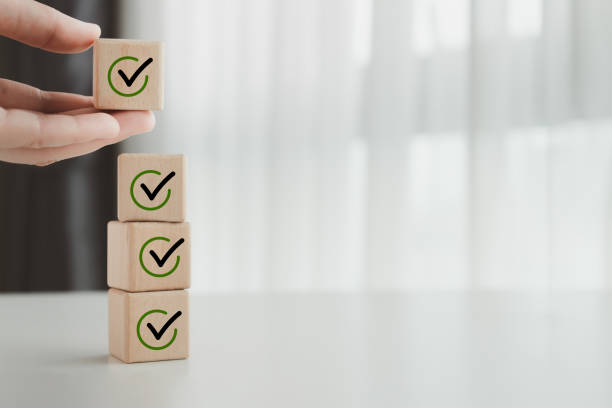 istock Checklist, Task list, Survey and assessment, Quality Control, Goals achievement and business success. To do list. Hand holding check mark for complete checklist on stack of wooden blocks. 1443207135