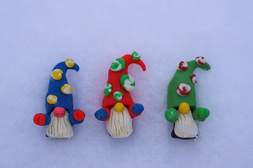 Figures of colorful dwarfs on a background of snow. Christmas decorations. Christmas toys.