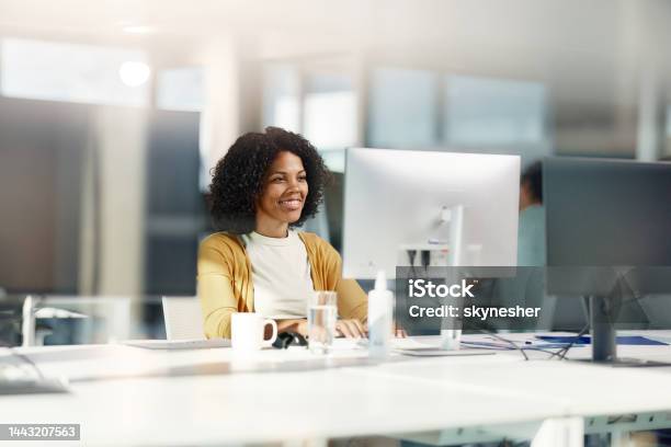 Happy black businesswoman working on desktop PC in the office.
