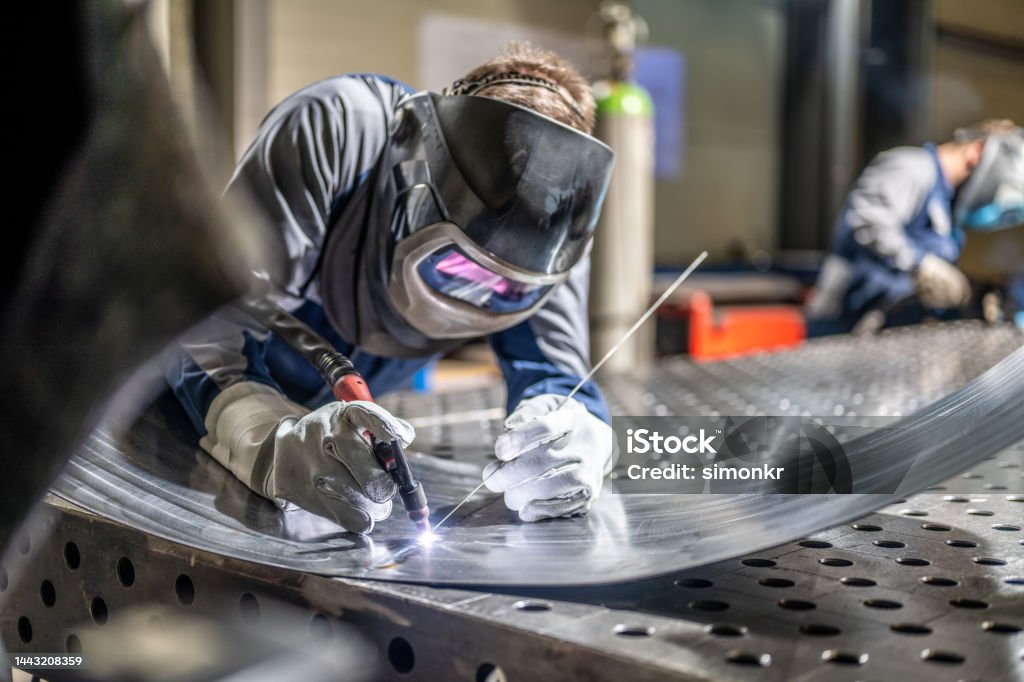 Welder welding sheet metal Male welder wearing helmet working with welding torch in factory. Welder Stock Photo