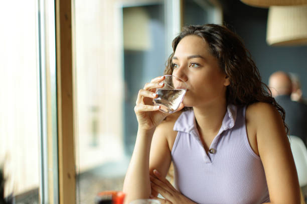istock Woman drinking water in a restaurant looking away 1443209659