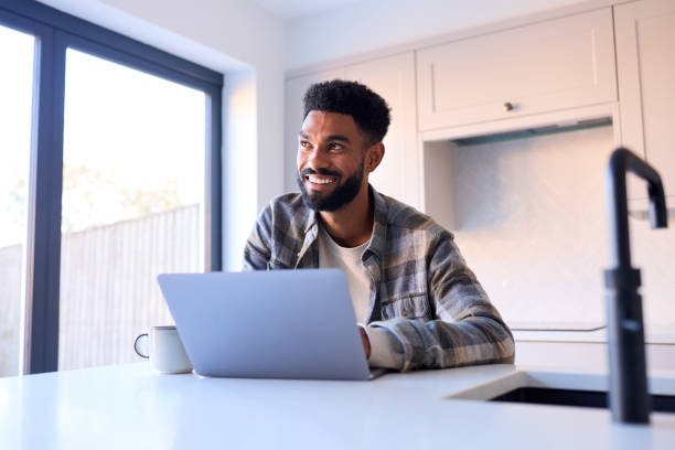 istock Man At Home Working On Laptop On Counter In Kitchen 1443209858