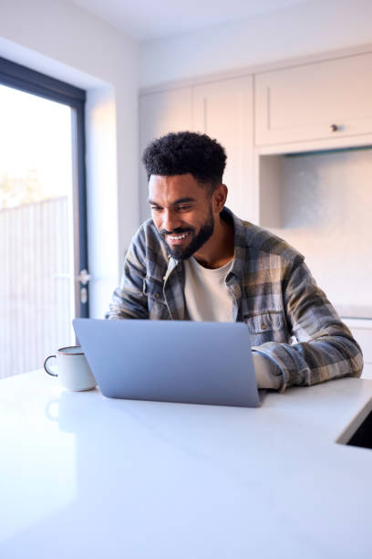 istock Man At Home Working On Laptop On Counter In Kitchen 1443209920