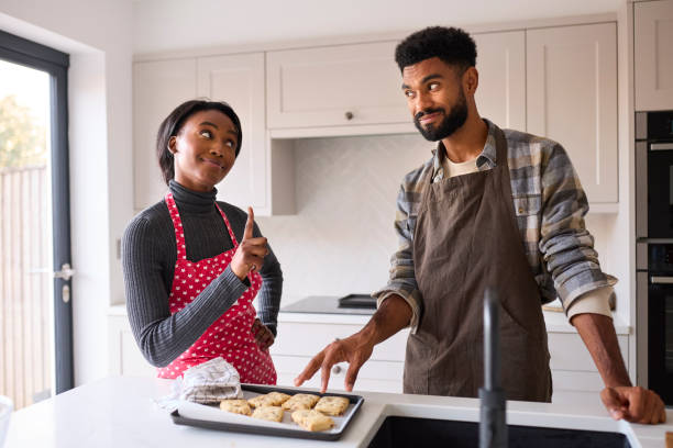 istock Couple At Home With Man Stealing Homemade Cookie From Tray In Kitchen 1443210903