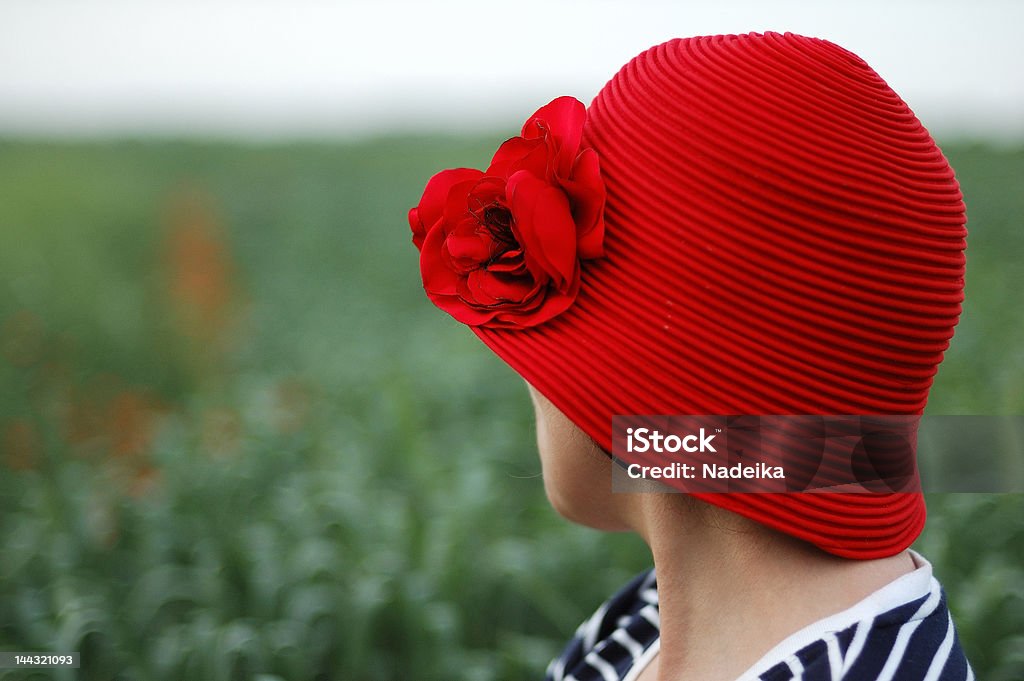 Woman wearing red hat against green field turned away Adult Stock Photo