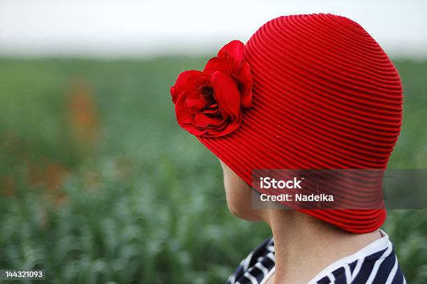 Woman Wearing Red Hat Against Green Field Turned Away Stock Photo - Download Image Now