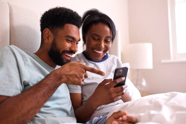 istock Young Couple At Home Both Looking At Mobile Phones In Bed Together 1443210966