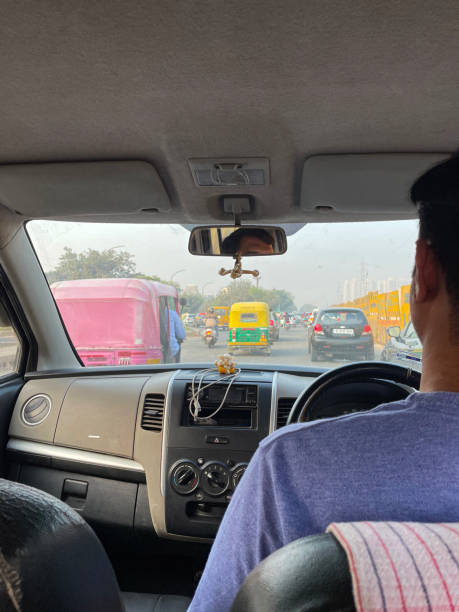 obraz indyjskiego mężczyzny jadącego autostradą / autostradą w prywatnym taksówce, czekając na ruch uliczny, korek, riksze samochodowe, żółte i zielone tuk tuki, samochody, motocykle, skupić się na pierwszym planie - accident taxi driving tourist zdjęcia i obrazy z banku zdjęć