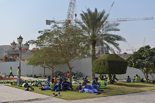 Foreign construction workers having a lunch break in the shadow of the extreme warmth of the arabic desert sun in Doha, Qatar.