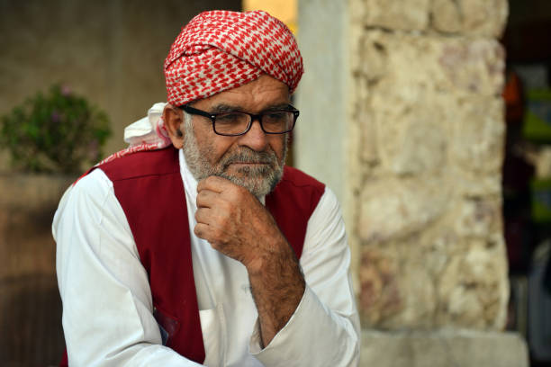 Grocery delivery man in traditional clothing waiting for customers on his wheelbarrow outside the souq area  in Doha, Qatar