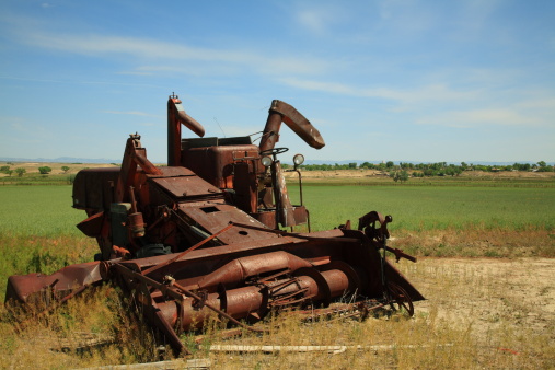 Old combine harvester abandoned in a field.  Rusting away in southern utah.