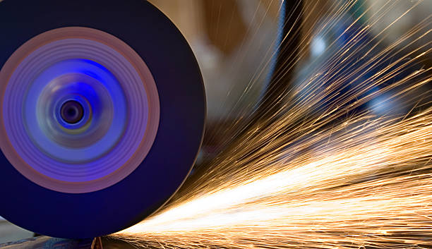 A grinder grinding a piece of metal and shooting sparks stock photo