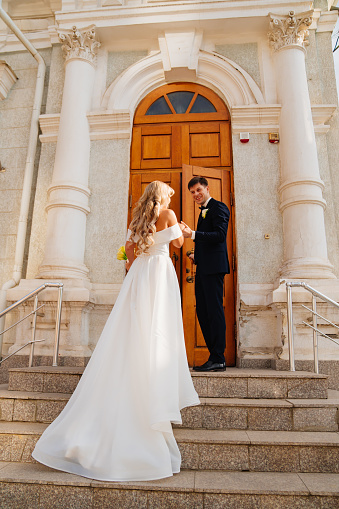 A bride and groom kissing in a church doorway.