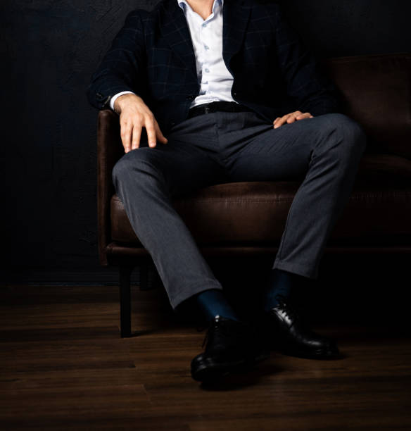 istock Unrecognizable stylish macho man sits relaxed on the sofa in the dark. 1443219509