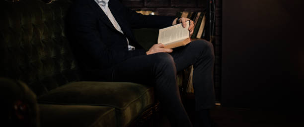 istock Stylish unrecognizable man reading a book while sitting on the couch. 1443222086
