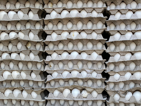 Stock photo showing close-up view of back of van transporting stacks of disposable cardboard trays filled with eggs for delivery to stores for sale.