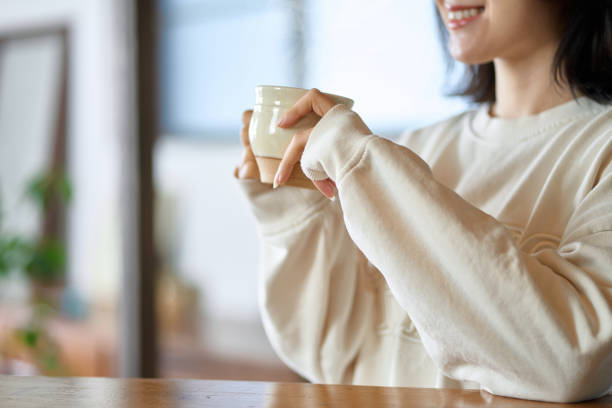 飲み物を飲みながらくつろぐアジア人女性 - 朝活 ストックフォトと画像