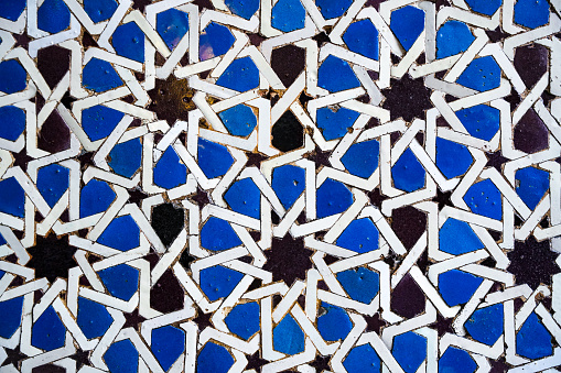 Geometric and seamless andalusian or moroccan islamic arabic star pattern in blue made out of ceramic tiles in Spain Sevilla
