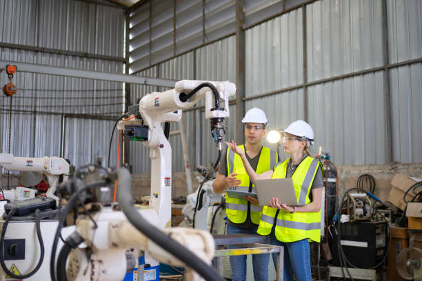 Blue collar workers are working with welding robot arm. stock photo