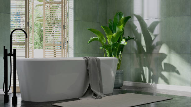 modern design of white ceramic ellipse bathtub, black stainless faucet and shower head and banana tree in dappled sunlight from window blinds on green granite tile wall and black marble floor luxury bathroom - indoors window courtyard elegance imagens e fotografias de stock