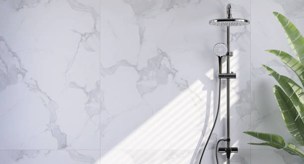 Modern and minimal bathroom design with shiny stainless steel rain shower, shower head on slide bar on beautiful white marble wall and banana tree with sunlight from window blinds stock photo