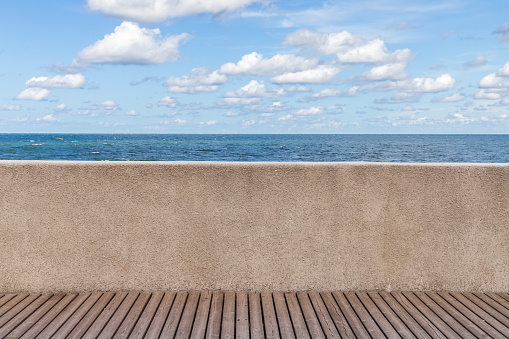 Empty promenade background photo with wooden floor and concrete railing mounted at the sea coast. Front view