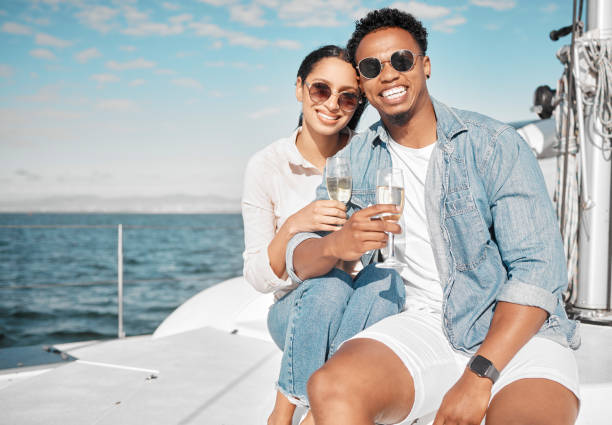 couple heureux sur le yacht avec sourire champagne et célébrer l’amour avec des vacances tropicales romantiques sur l’océan. sortir avec un homme et une femme sur un bateau de luxe sur l’eau de la plage ou la mer avec un verre de vin pour célébr - champagne celebration glass black photos et images de collection