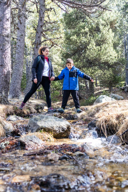 istock Woman and kid crossing a river on the mountain 1443233785