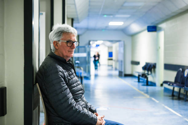 Worried senior man waiting in hospital corridor stock photo