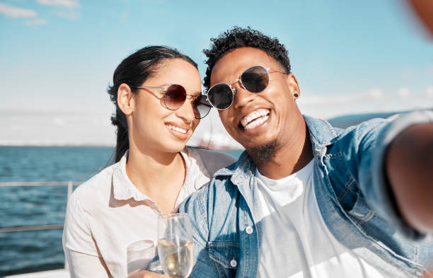 Couple selfie on yacht in ocean celebrate with champagne on vacation or holiday in summer. Happy young man with luxury wine, cruise at sea with woman for celebration or honeymoon travel on ship Couple on ocean with yacht celebrate with champagne on romantic vacation or holiday in summer. Happy young man with luxury wine on cruise at sea with woman for celebration or honeymoon travel on ship yacht selfie stock pictures, royalty-free photos & images