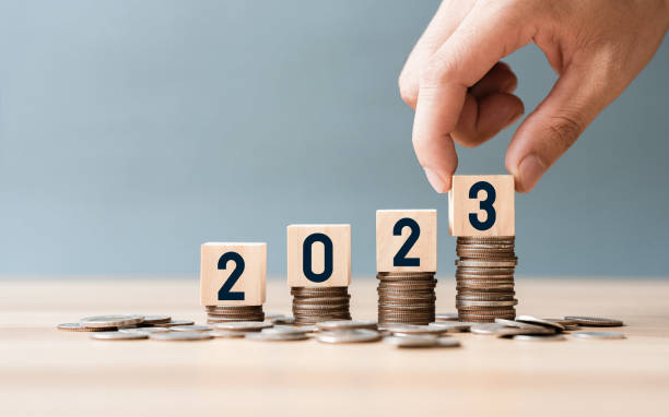 istock Hand place wooden cube 2023 on top stack of coins with sky blue background and copy space. saving money and financial plan concept for investment in new year 2023. 1443233979