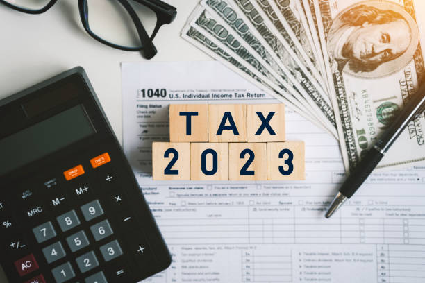 나무 큐브로 된 세금 텍스트와 세금 또는 부가가치세 양식 문서를 작성하여 정부에 지불하기 위해 개인 소득세 신고서를 작성하십시오. 2022년부터 2023년까지의 계산 세금 신고서. - tax preparation 뉴스 사진 이미지