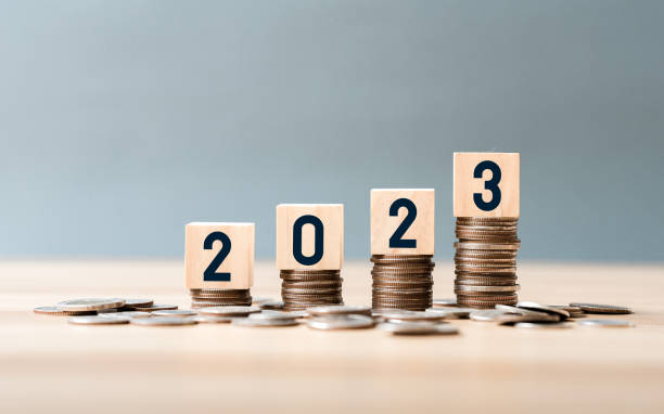 istock wooden cube year 2023 on top stack of coins with sky blue background and copy space. saving money and financial plan concept for investment in new year 2023. 1443234030