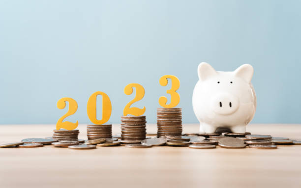 Gold wooden number year 2023 on top stack of coins with sky blue background and copy space. saving money and financial plan concept for investment in new year 2023. stock photo