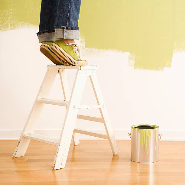Woman on ladder painting. stock photo