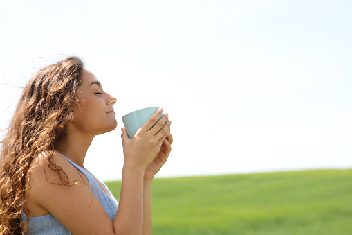 Woman smelling coffee in a field