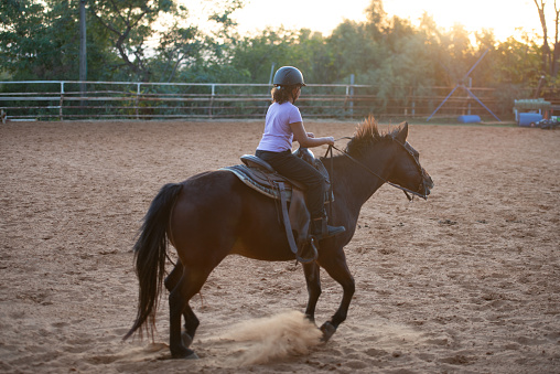 Girl enjoying horse ride at sunset.