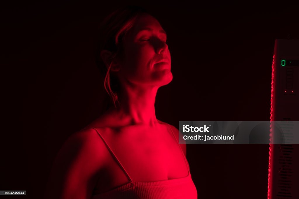 Woman getting red light therapy from a red light device Woman getting red light therapy in a beauty salon. Mature woman getting anti-aging treatment from a red light device. Skin care and rejuvenation procedure. Physical Therapy Stock Photo