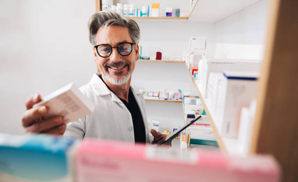 farmacéutico leyendo la etiqueta de un medicamento en una farmacia - pharmacy medicine pharmacist storage room fotografías e imágenes de stock