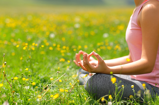Close up of a woman doing yoga exercise in a field