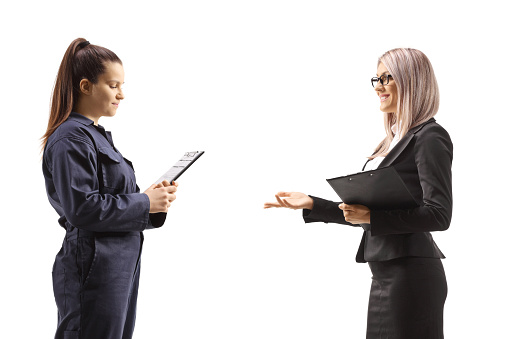 Profile shot of a businesswoman talking to a female auto mechanic isolated on white background