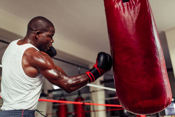 istock Determined African boxer landing a punch on a red leather bag 1443238336