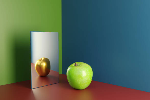 A green apple in a mirror reflecting golden version of himself stock photo