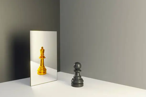 Black colored chess pawn standing in front of a mirror that reflects himself as a king. (3d render)