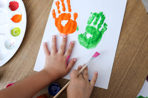 Children's master class in drawing, the child makes a handprint with paint stock photo