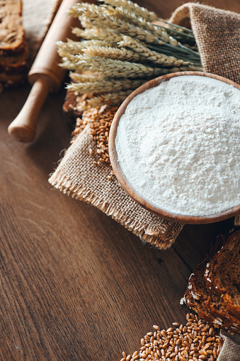 Bread, grains, ears of wheat and flour on a wooden background, bakery advertising banner