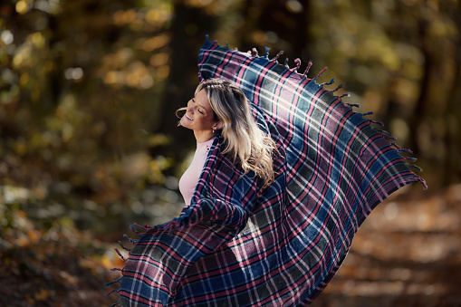 carefree woman having fun while spinning during autumn day in nature. Copy space.