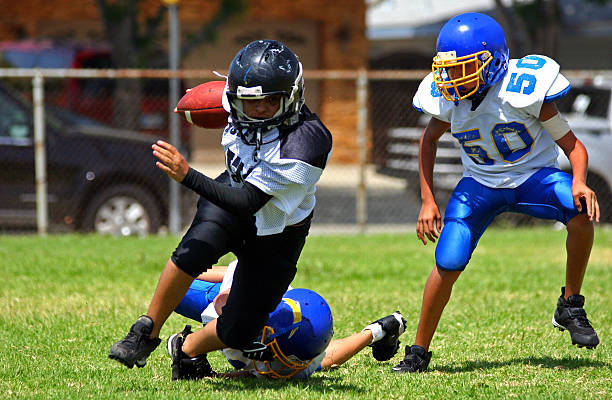Breaking the Tackle Young american football player running back breaking away from an attempted tackle. All logos and trademarks from uniforms, helmets and cleats have been removed in Photoshop charging sports photos stock pictures, royalty-free photos & images