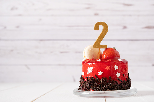 The number Two on a red birthday cake on a light background.